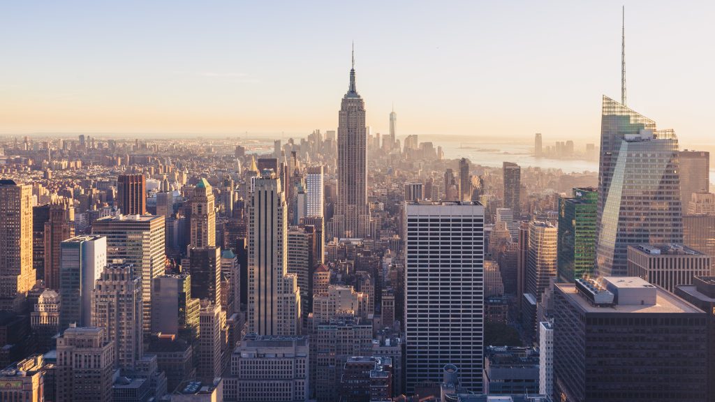 New York City skyline at sunset featuring the Empire State Building and modern skyscrapers, capturing the vibrant energy and architectural diversity of the "City that Never Sleeps."