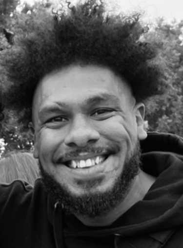 Smiling man with curly hair in a casual black hoodie, showcasing a joyful expression, reflecting the positive experiences shared about travel planning with Once Upon A Trip Travel.